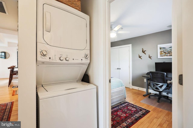 laundry room with laundry area, baseboards, a ceiling fan, light wood-style flooring, and stacked washer / drying machine