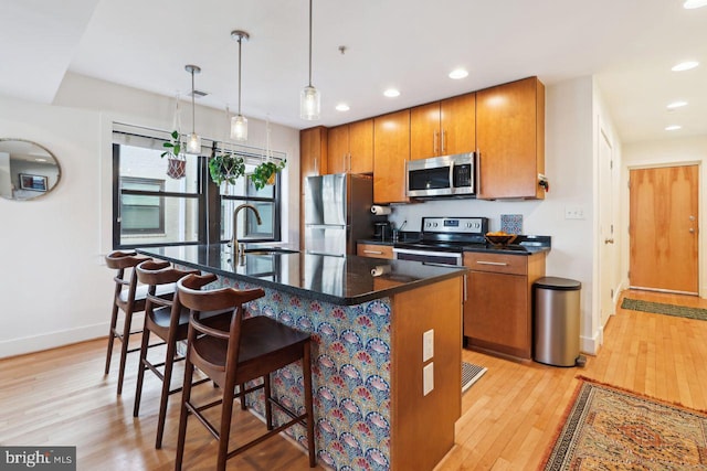 kitchen with appliances with stainless steel finishes, dark countertops, brown cabinets, and light wood-style floors