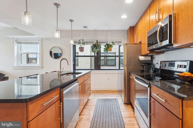 kitchen featuring stainless steel appliances, plenty of natural light, a sink, and brown cabinets