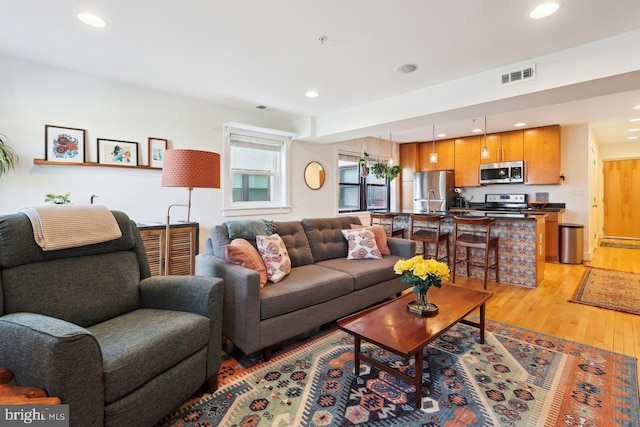 living area featuring light wood-style floors, recessed lighting, and visible vents