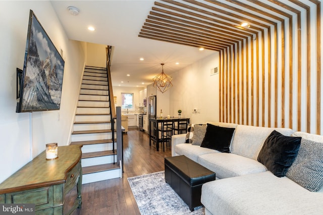 living room with dark wood-style floors, recessed lighting, visible vents, and stairs