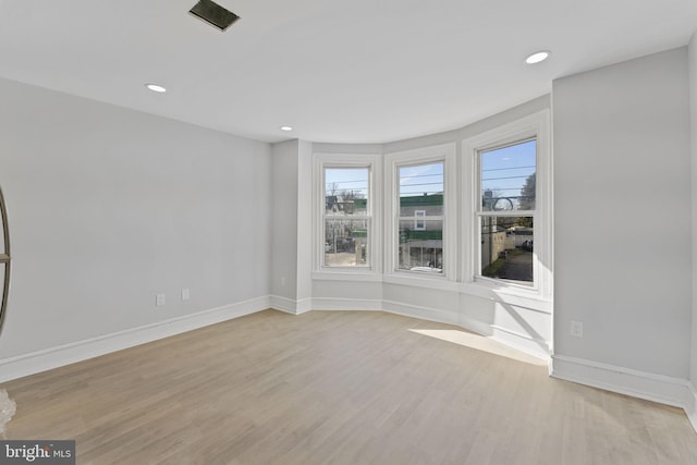 empty room featuring light wood finished floors, recessed lighting, and baseboards