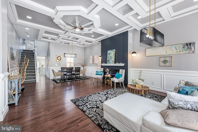 living room featuring a decorative wall, wood finished floors, a ceiling fan, stairs, and beam ceiling