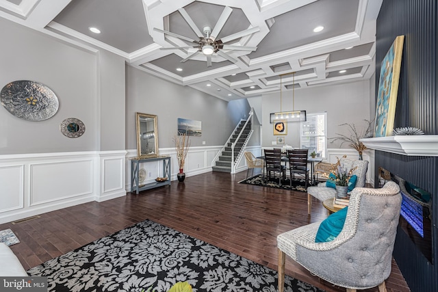 living area with coffered ceiling, wood finished floors, visible vents, and stairs