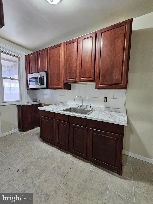 kitchen featuring stainless steel microwave, a sink, and baseboards