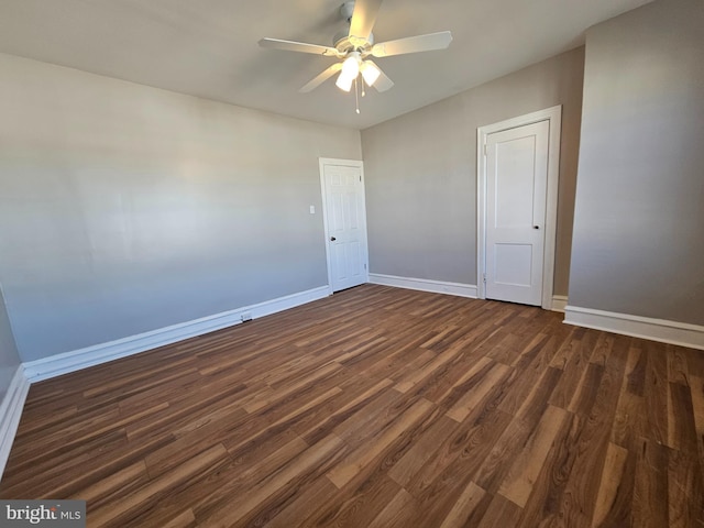 spare room with dark wood-style flooring, ceiling fan, and baseboards