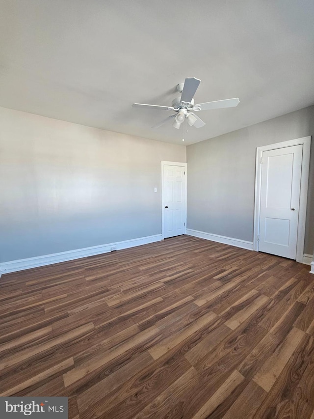 unfurnished room with ceiling fan, dark wood finished floors, and baseboards