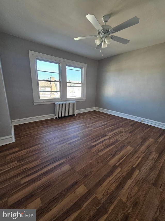 empty room with radiator, baseboards, and dark wood finished floors