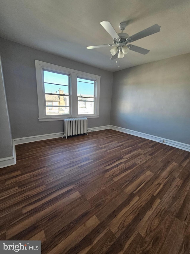 spare room with ceiling fan, dark wood-style flooring, radiator heating unit, and baseboards