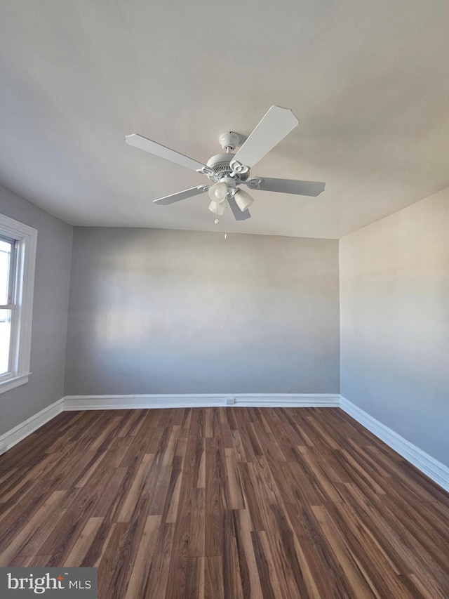 unfurnished room with a ceiling fan, baseboards, and dark wood-style flooring