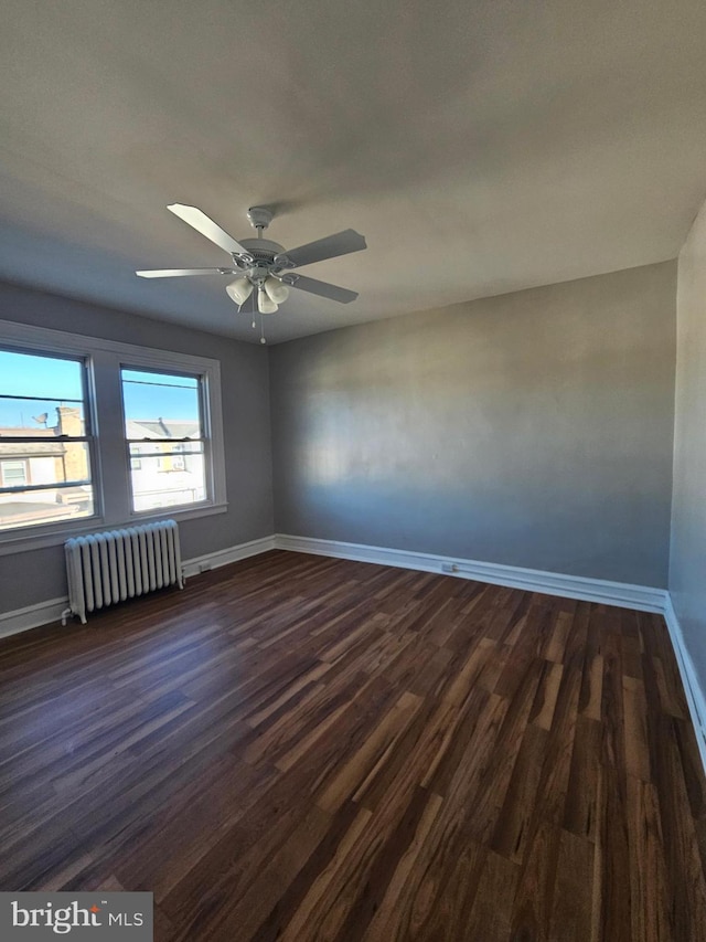 unfurnished room with baseboards, ceiling fan, dark wood-type flooring, and radiator