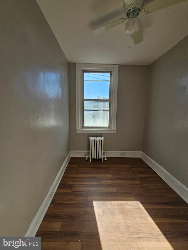 empty room with a ceiling fan, baseboards, radiator heating unit, and wood finished floors