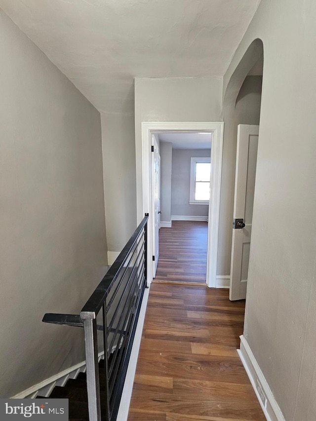 corridor featuring wood finished floors, an upstairs landing, and baseboards