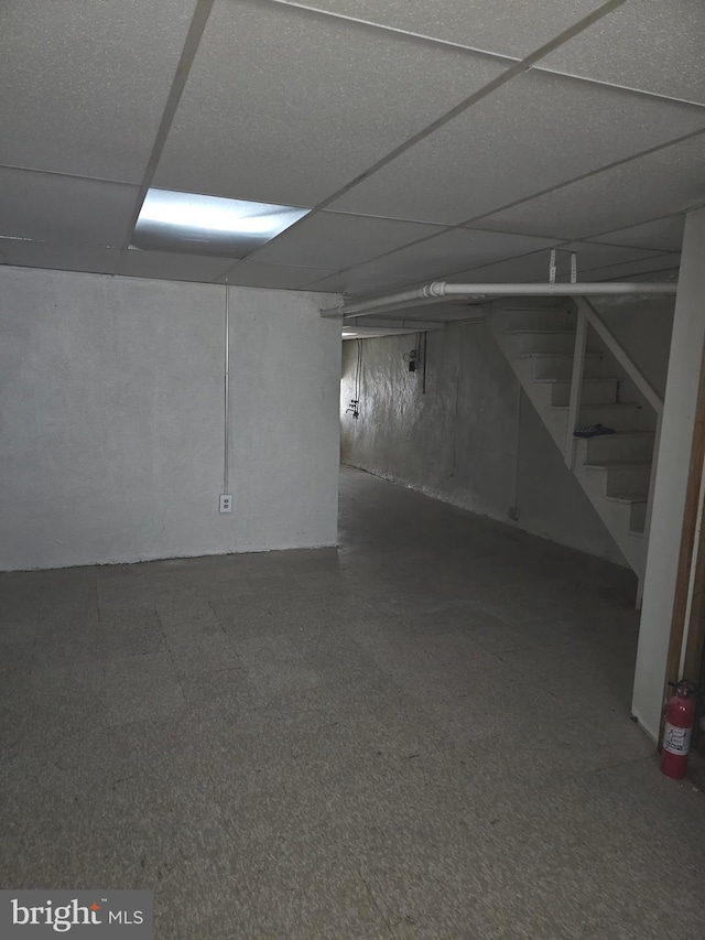 finished basement featuring a paneled ceiling and stairway