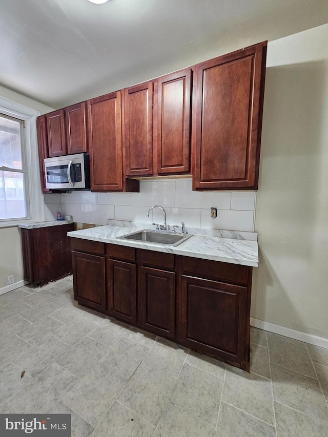 kitchen with stainless steel microwave, a sink, and baseboards