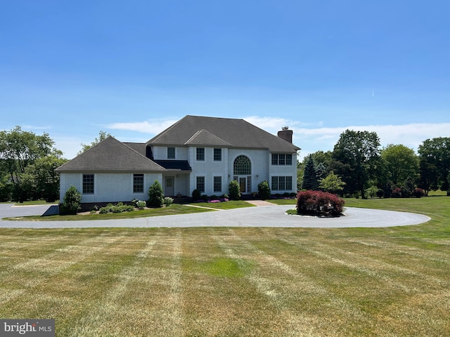 view of front of house featuring a chimney and a front yard