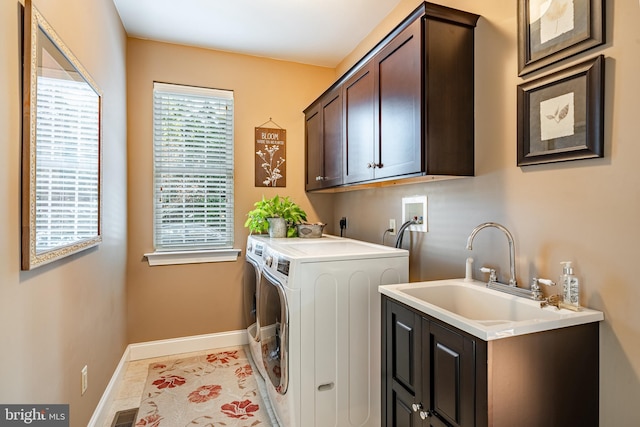 washroom featuring cabinet space, visible vents, a sink, washer and dryer, and baseboards