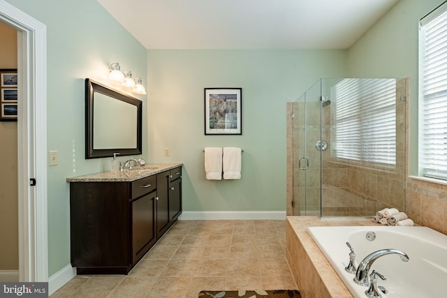 bathroom with a stall shower, a garden tub, vanity, and baseboards