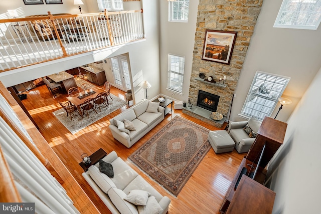 living room featuring a fireplace, a towering ceiling, and wood finished floors