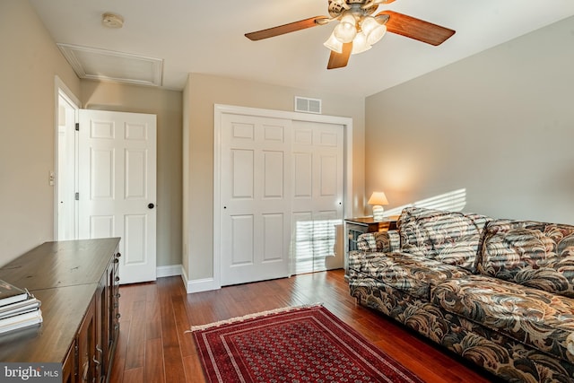 living area featuring dark wood-style floors, visible vents, baseboards, and a ceiling fan