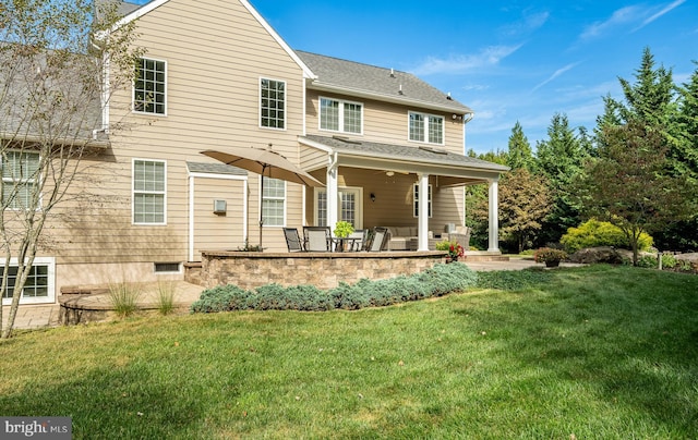 rear view of property featuring a shingled roof, a lawn, and a patio