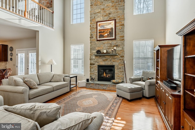 living room featuring light wood-style floors, a fireplace, and a high ceiling