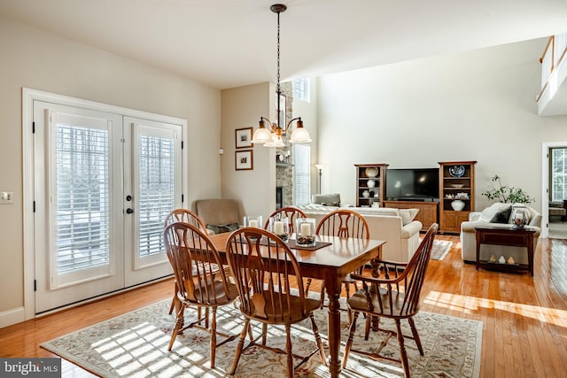 dining area with french doors, light wood finished floors, and an inviting chandelier