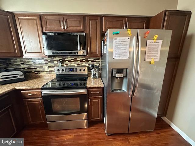 kitchen featuring decorative backsplash, appliances with stainless steel finishes, baseboards, and dark wood-style flooring