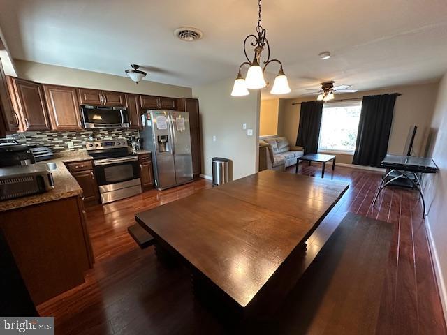 dining space featuring visible vents, baseboards, dark wood-type flooring, and a ceiling fan