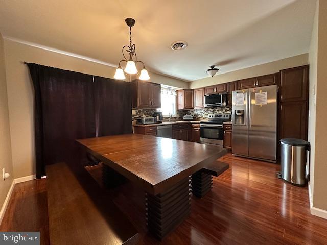 kitchen with backsplash, stainless steel appliances, dark wood-type flooring, and dark brown cabinetry