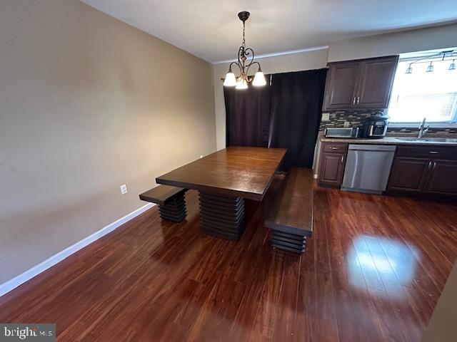 dining space featuring baseboards, a notable chandelier, and dark wood finished floors