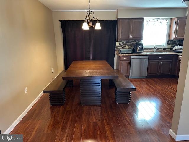 kitchen featuring a sink, tasteful backsplash, stainless steel dishwasher, and dark wood-style floors