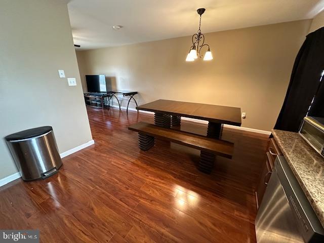 dining room with a notable chandelier, baseboards, and wood finished floors