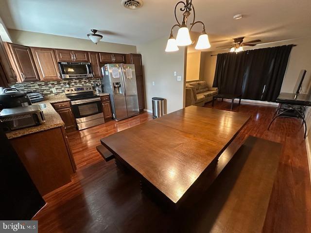 dining area featuring a ceiling fan, visible vents, and dark wood-style flooring