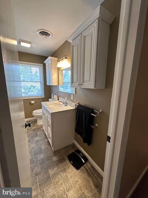 bathroom featuring visible vents, toilet, vanity, and baseboards