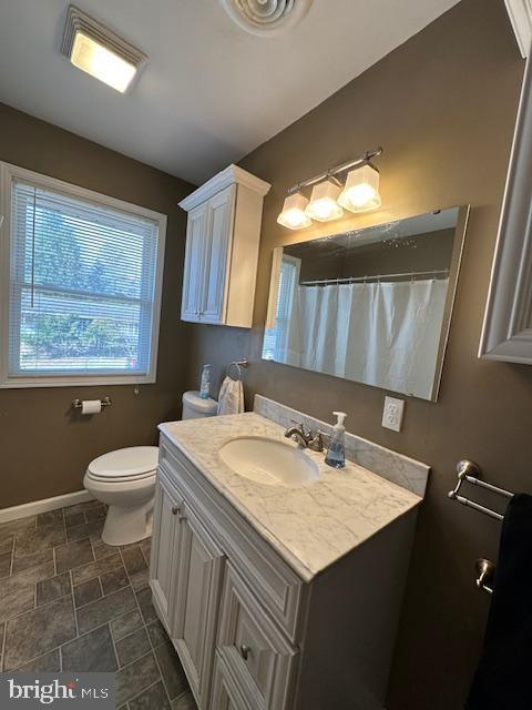 bathroom featuring curtained shower, toilet, vanity, and baseboards