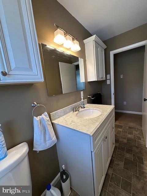 bathroom with toilet, vanity, and baseboards