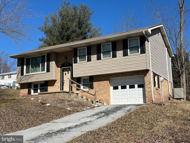 bi-level home featuring brick siding, driveway, and a garage