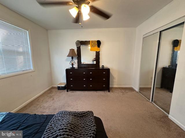 carpeted bedroom featuring baseboards, a closet, and ceiling fan