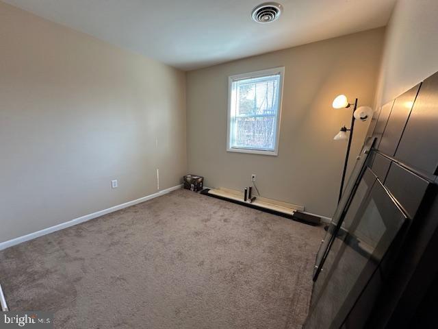 carpeted empty room with visible vents and baseboards