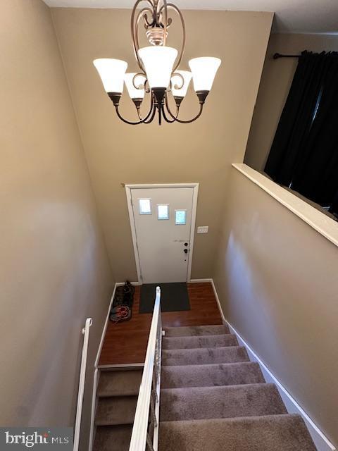 stairs with baseboards, a notable chandelier, and wood finished floors