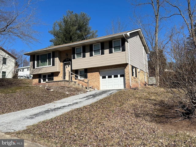 raised ranch featuring a garage, brick siding, and driveway