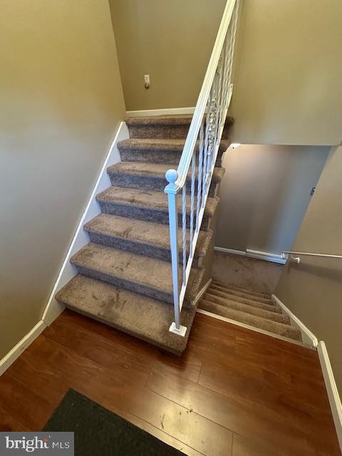 staircase with baseboards and wood finished floors