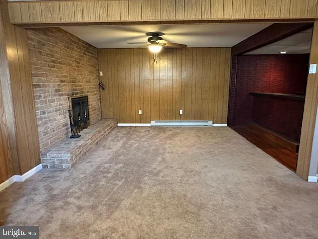 unfurnished living room with wooden walls, a brick fireplace, a baseboard heating unit, beamed ceiling, and carpet floors