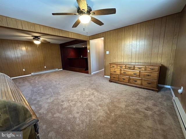 unfurnished bedroom with a baseboard heating unit, carpet, wood walls, and a baseboard radiator