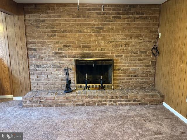 interior details with baseboards, a brick fireplace, wood walls, and carpet flooring