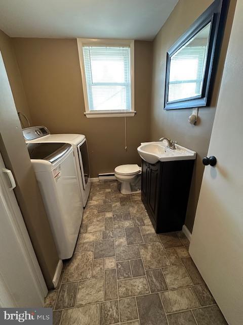 washroom featuring baseboard heating, laundry area, plenty of natural light, washer and dryer, and a sink