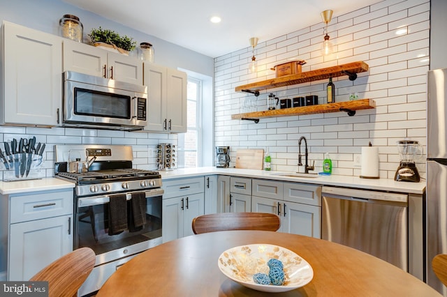 kitchen featuring appliances with stainless steel finishes, light countertops, a sink, and decorative backsplash