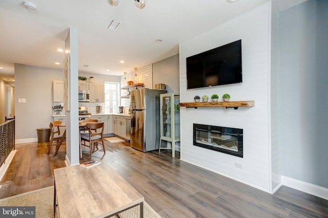 living room with a glass covered fireplace, recessed lighting, wood finished floors, and baseboards