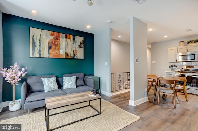 living room featuring baseboards, wood finished floors, and recessed lighting